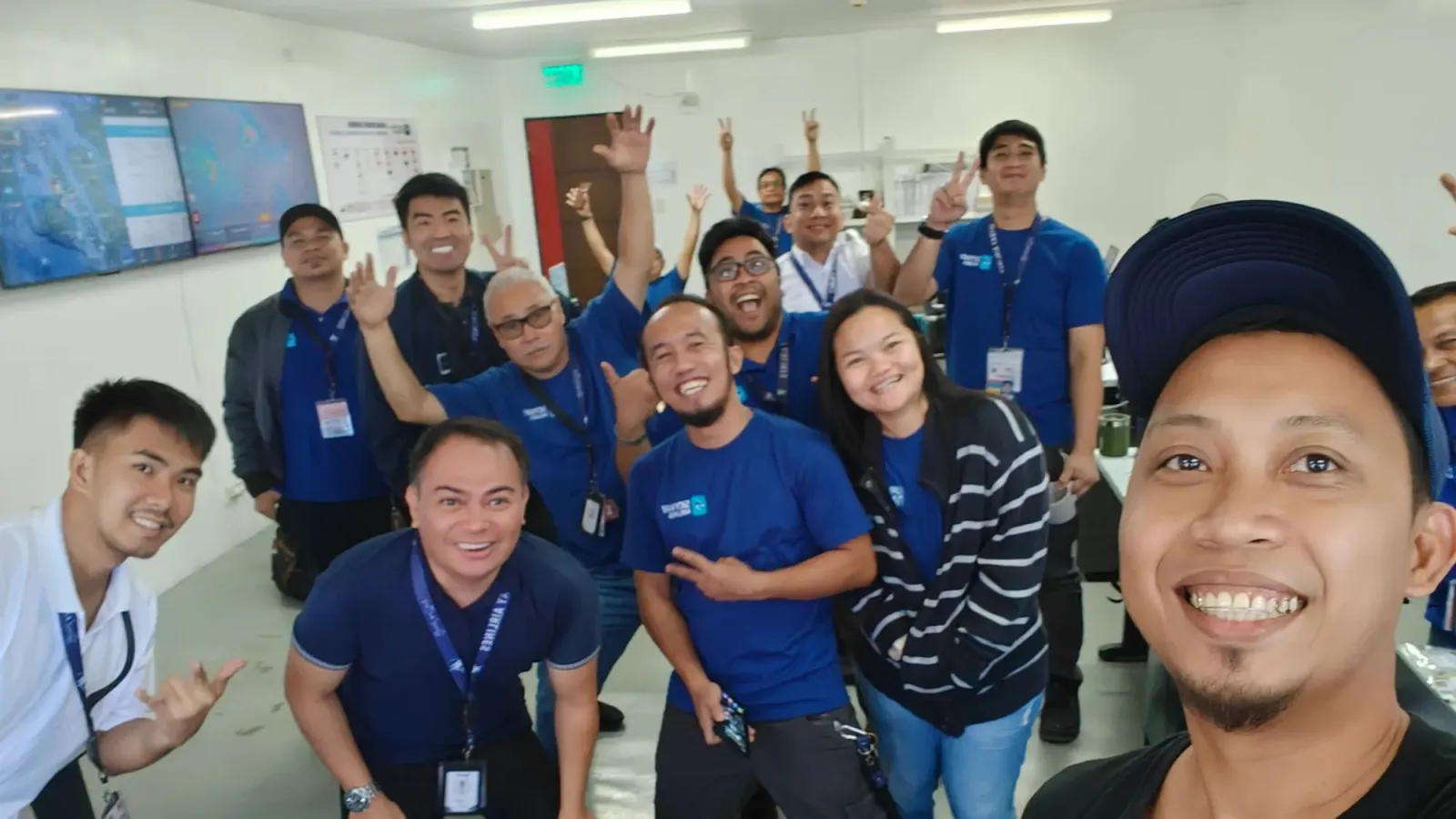 An airline operations team crowded into their control room, waving at the camera