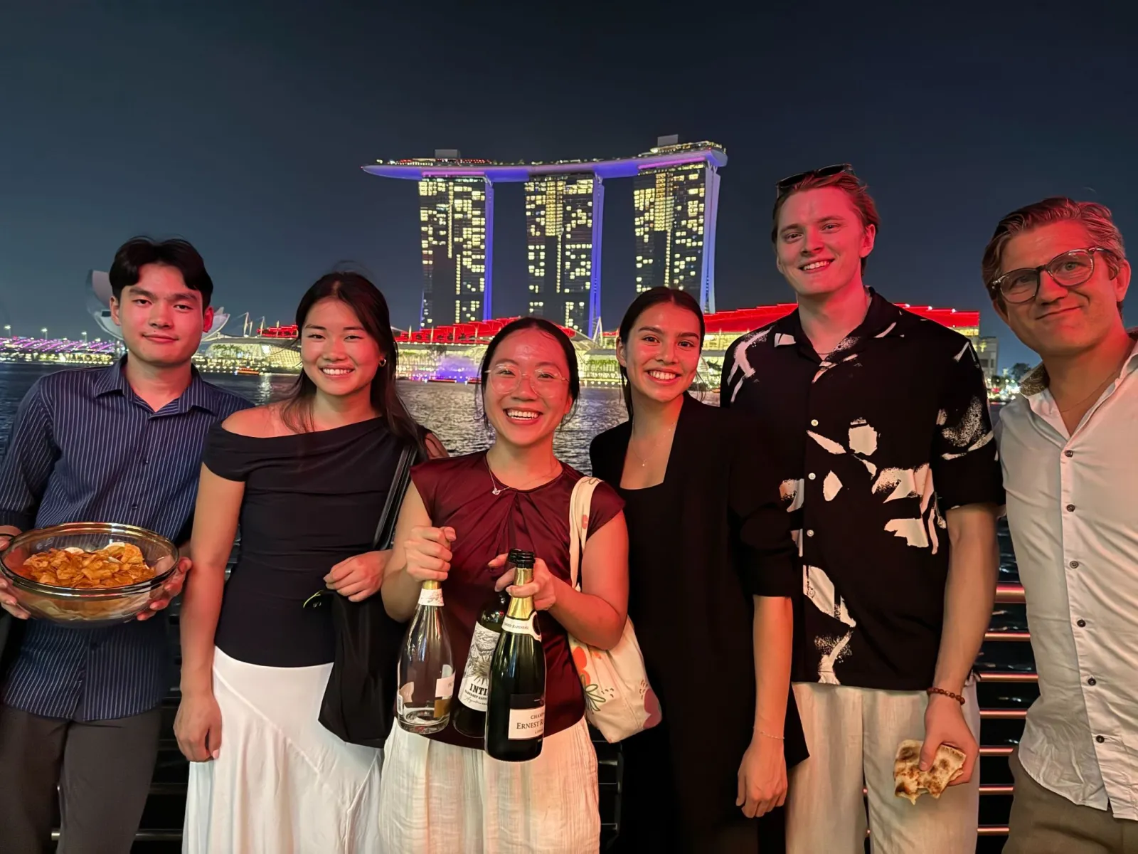 Six associates on deck with Marina Bay Sands lit up behind them